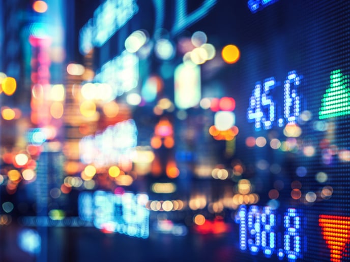 Abstract financial markets numbers overlaying cityscape with multicolor lights.