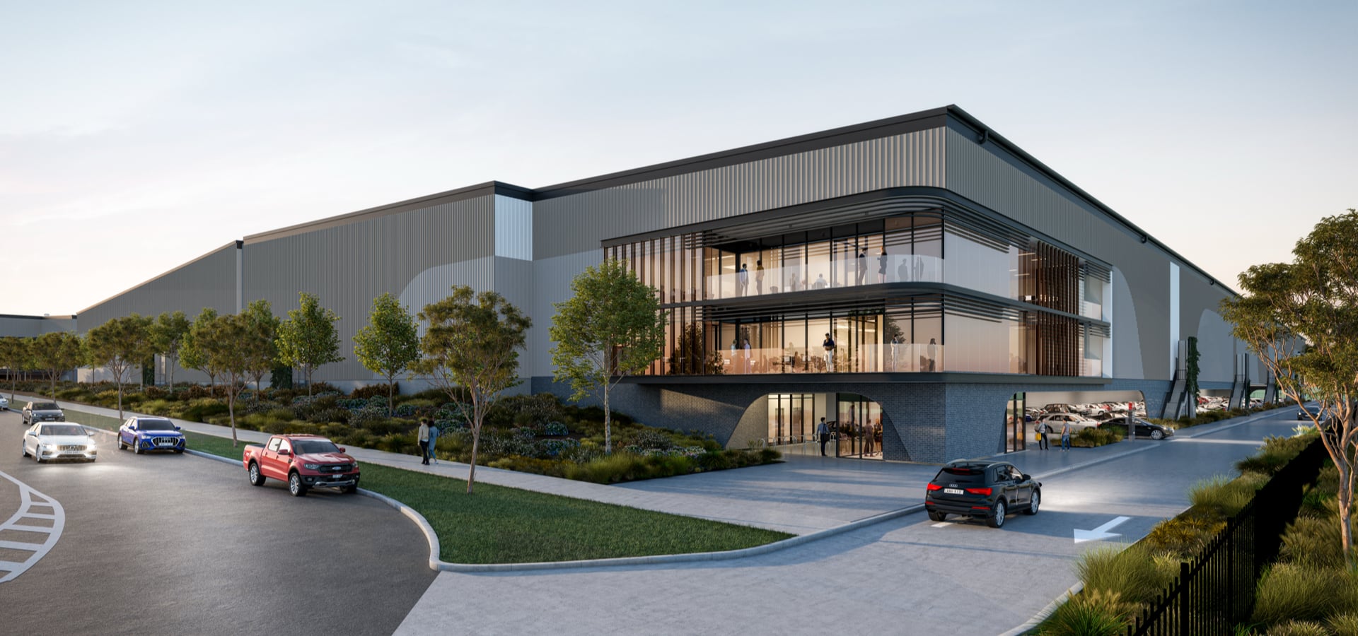An industrial building with trees and cars parked in front of it.